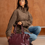Sac à main Alba bordeaux porté à la main, femme assise