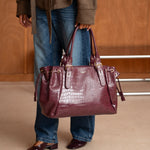 Sac à main Alba bordeaux porté à la main, femme debout