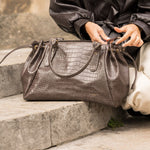 Sac à main Alba chocolat posé sur les genoux, femme assise