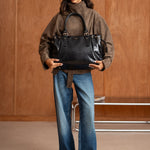 Sac à main Alba noir tenu à deux mains, femme debout