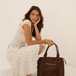 Sac à main Alva chocolat posé au sol, femme assise