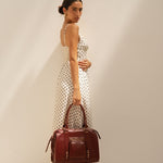 Sac à main Ariana bordeaux porté à la main, vue de profil