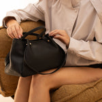 Sac à main Jane noir posé sur les genoux