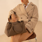 Sac à main Jane taupe porté à la main, femme assise