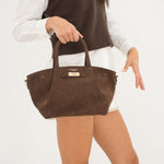Sac à main Milae chocolat porté à la main, femme debout