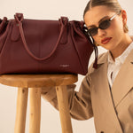 Sac cabas Elios bordeaux posé sur un tabouret, femme accoudée