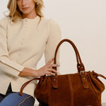 Garance camel tote bag on a wooden bench beside a seated woman