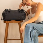 Sac cabas Elios bleu marine posé sur un tabouret, femme assise à côté