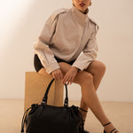 Sac cabas Elios noir posé au sol, femme assise