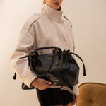 Sac à main Iria noir porté à la main, vue de face
